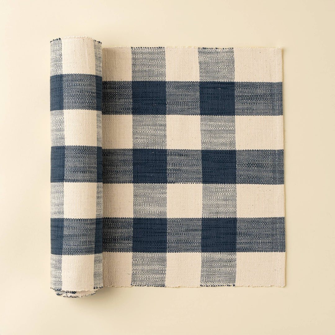 Rolled-up blue and white checkered table runner on a beige background