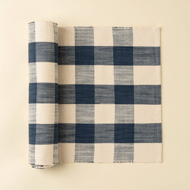 Rolled-up blue and white checkered table runner on a beige background