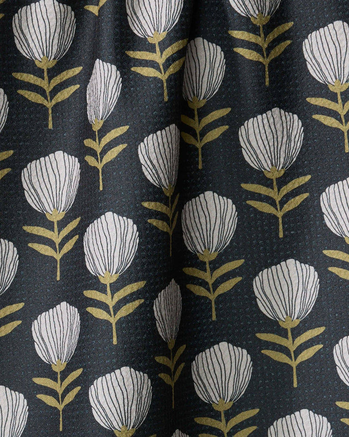 Geometry towel with a floral pattern featuring white flowers and green leaves on a dark background