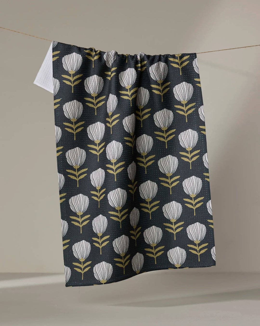 Floral patterned towel hanging on a line against a neutral background