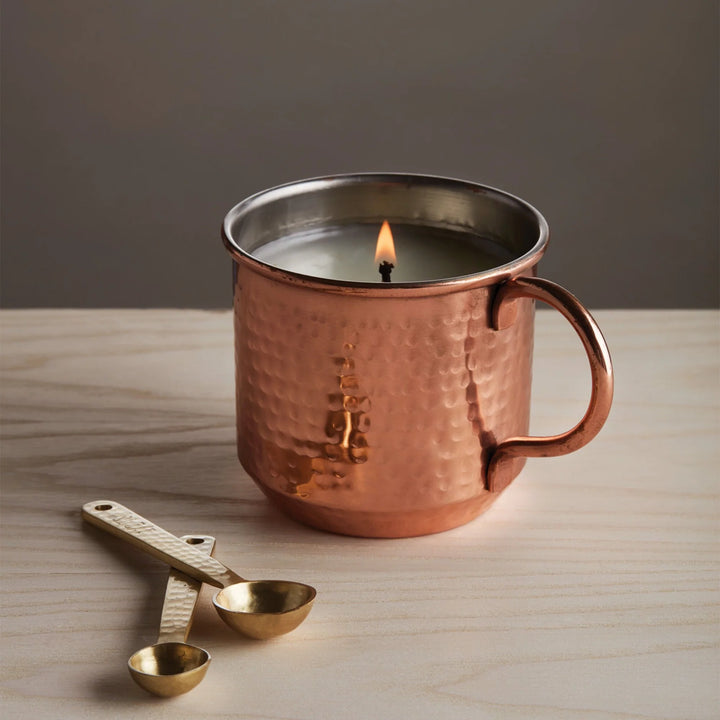 Copper mug with a lit candle inside 