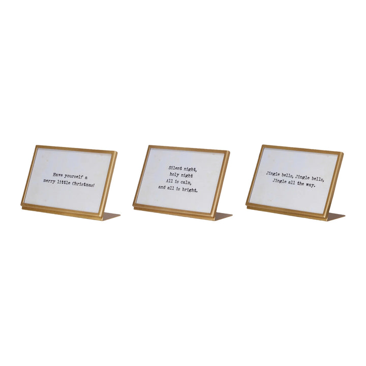 gold finish metal and glass frames with easels and Christmas-themed sayings written in them.