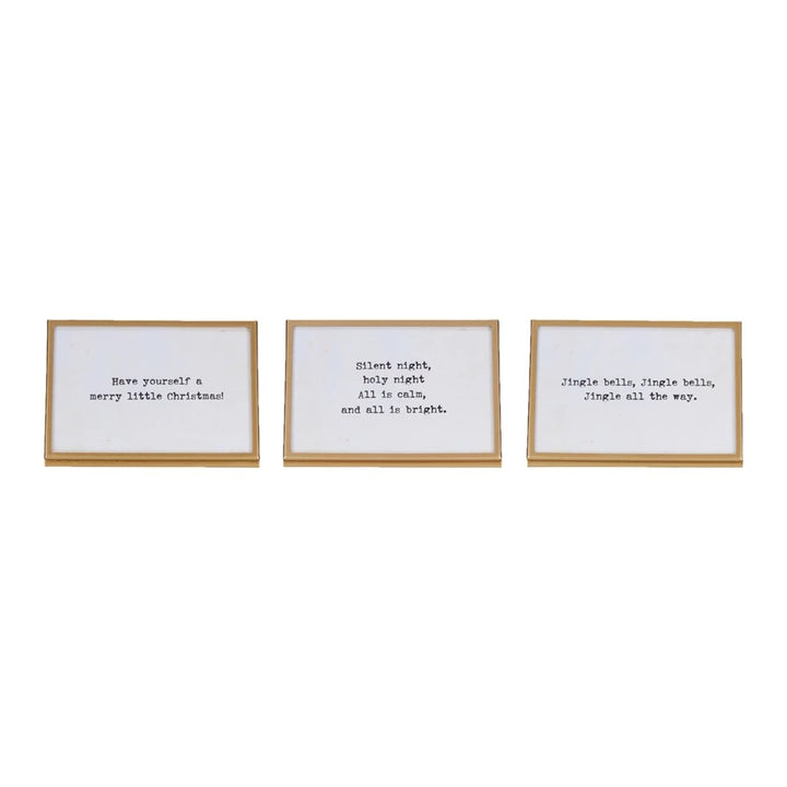 Three gold finish metal and glass frames with easels and Christmas-themed sayings written in them.