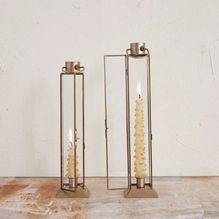 Two gold-finished metal and glass lantern taper holders with candles, one large and one small, against a white background.